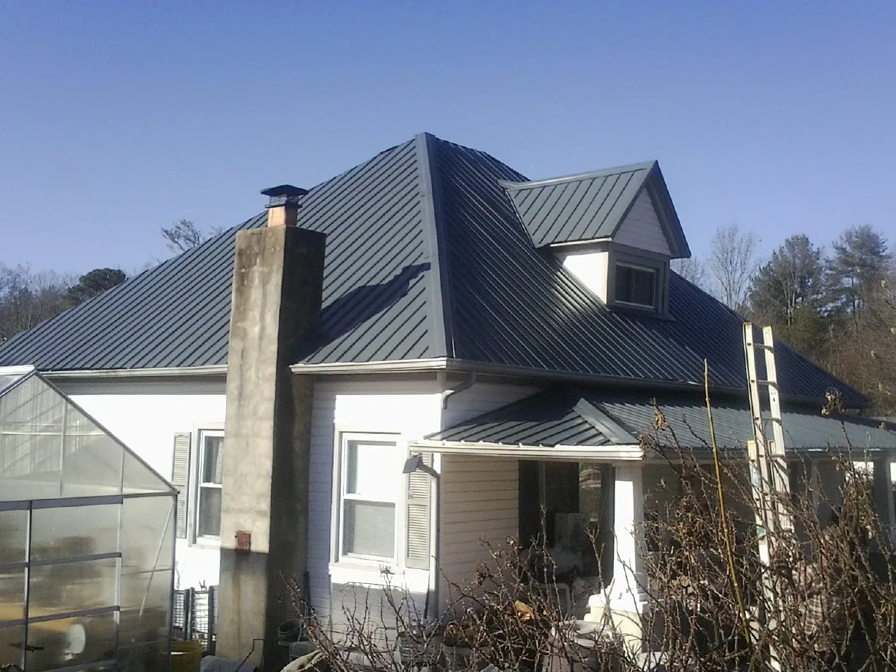 Dark blue standing seam metal roof on a white farmhouse with dormer — Slate & Tile Roof Repair by Roofing Brothers in Kimball