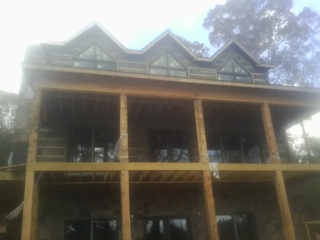 Dormers and porch framing on a large log home under construction — Roof Coating work by our crew in Kimball