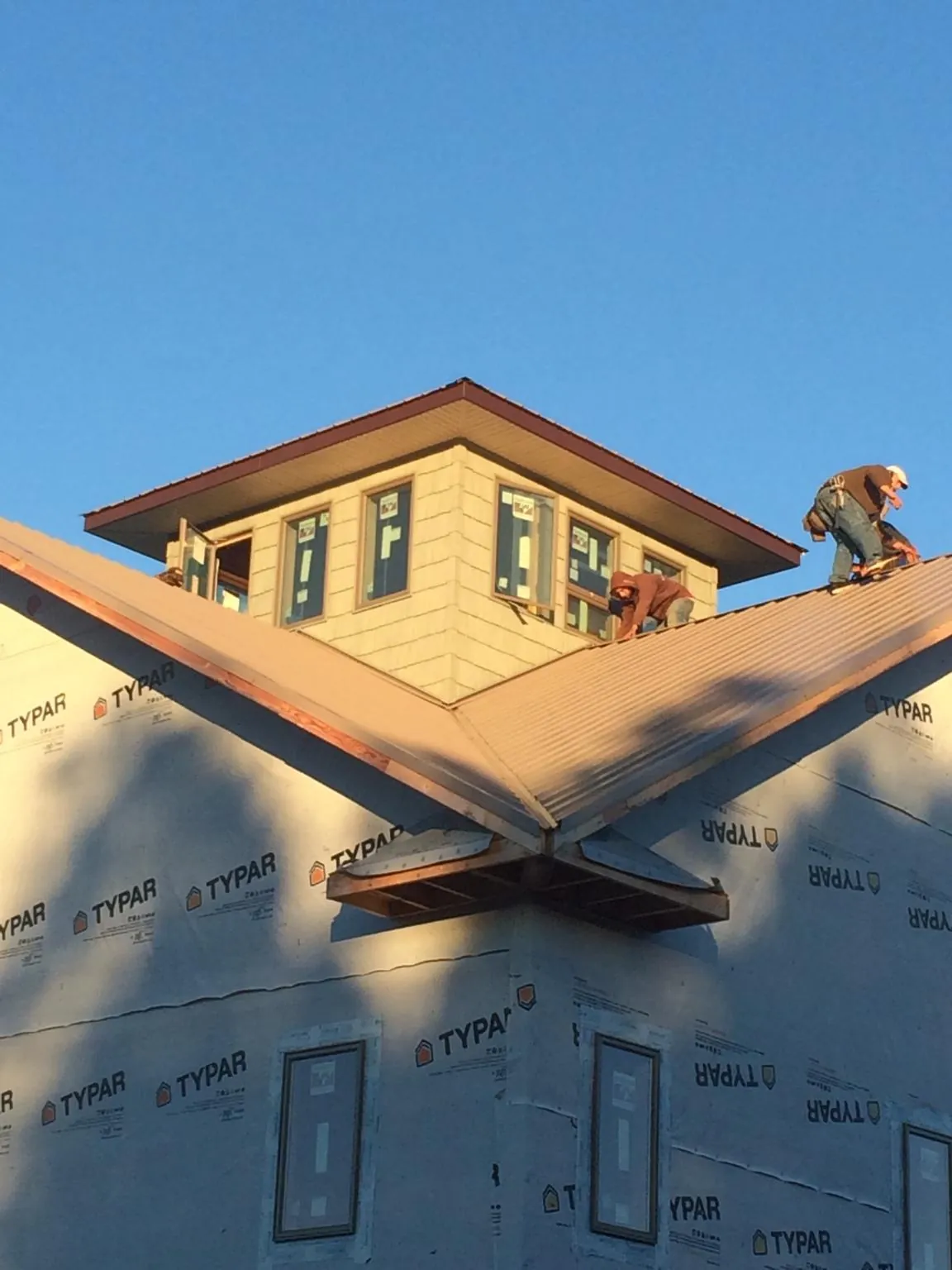 Roofers working around a rooftop cupola on a new metal roof at sunset — Roof Waterproofing in Kimball by Roofing Brothers